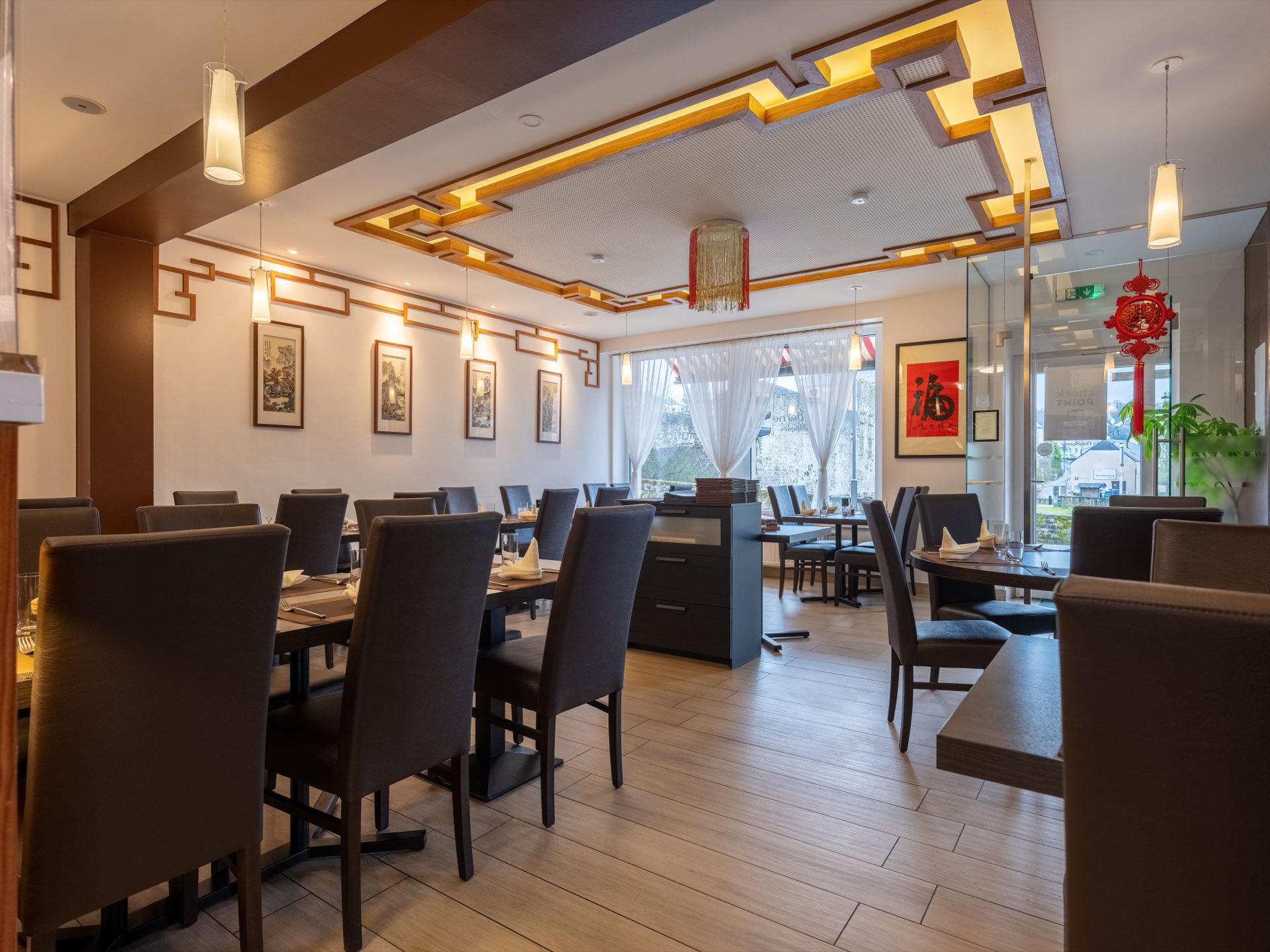 卢森堡克里希 Asie Moderne 现代亚洲餐厅的用餐厅：摆好的餐桌、木质装潢，以及中式图案天花板下的红色灯笼